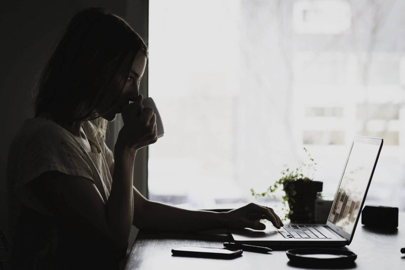 Femme qui boit un café devant son ordinateur portable